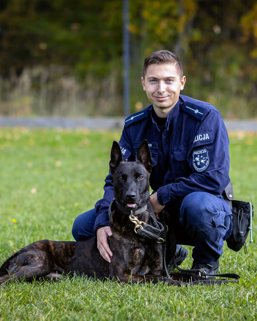 Pies służbowy K9 z policjantem-przewodnikiem podczas służby, fotografia psa policyjnego